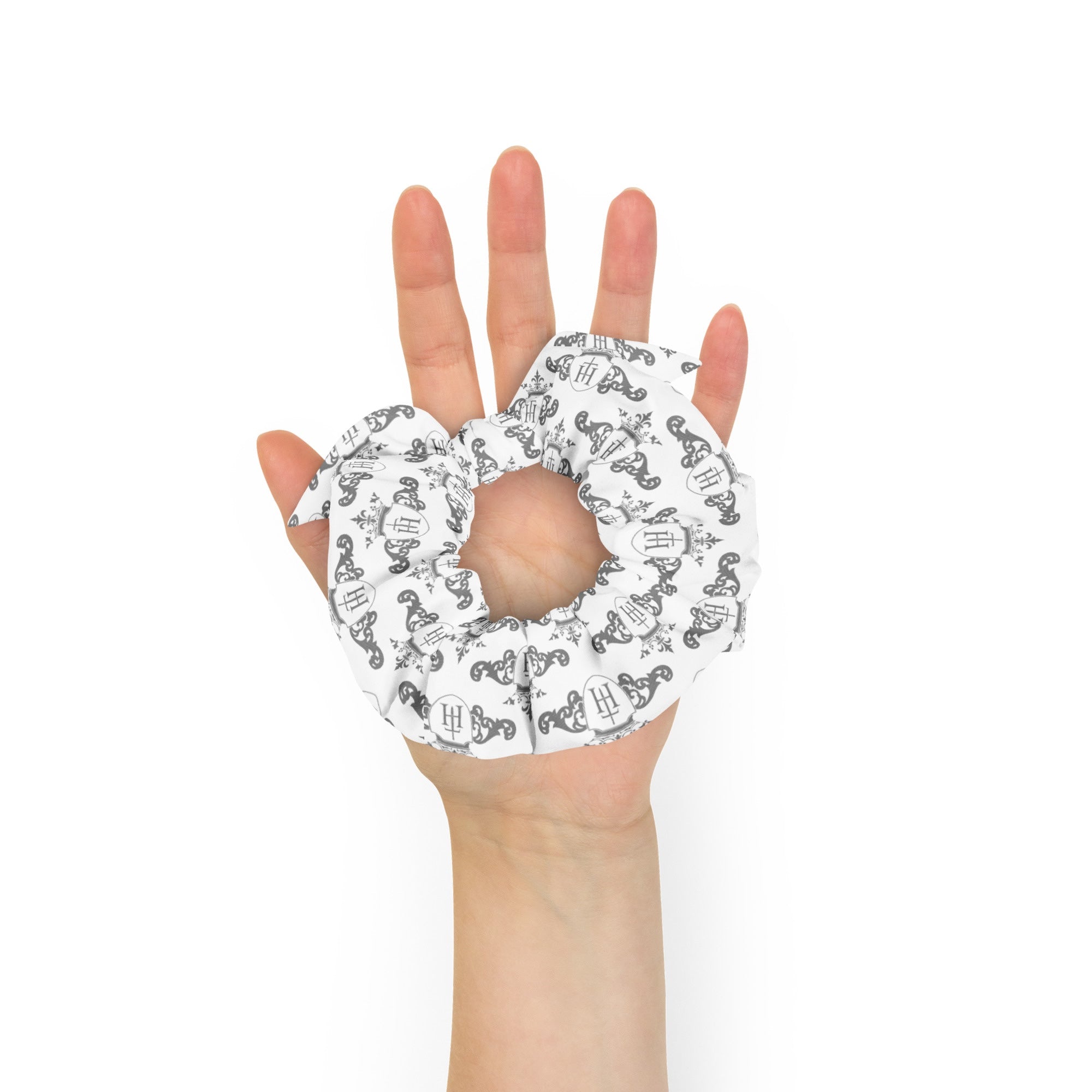 Hand holding a scrunchie with a black and white pattern on a white background