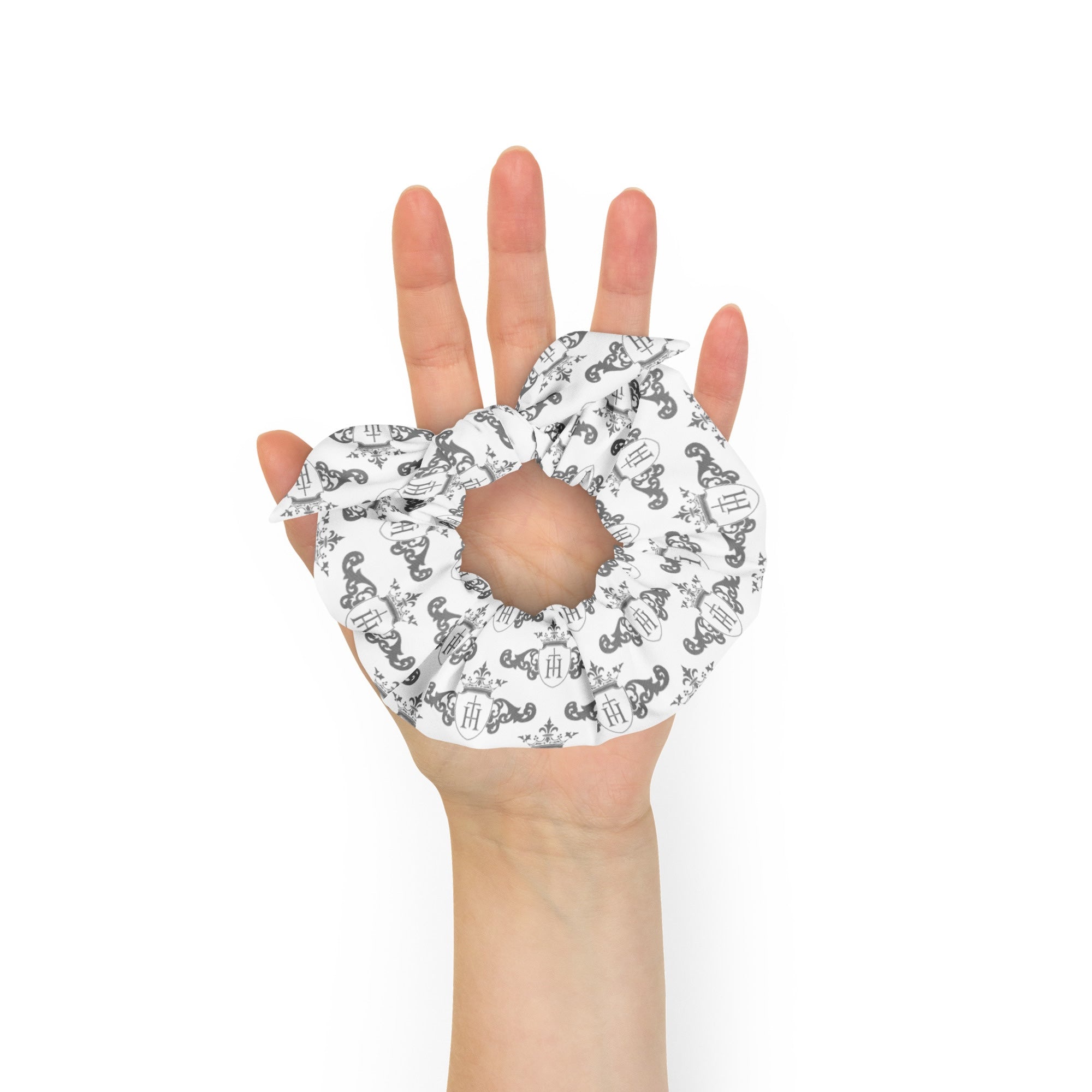 Hand holding a white scrunchie with black patterns on a white background