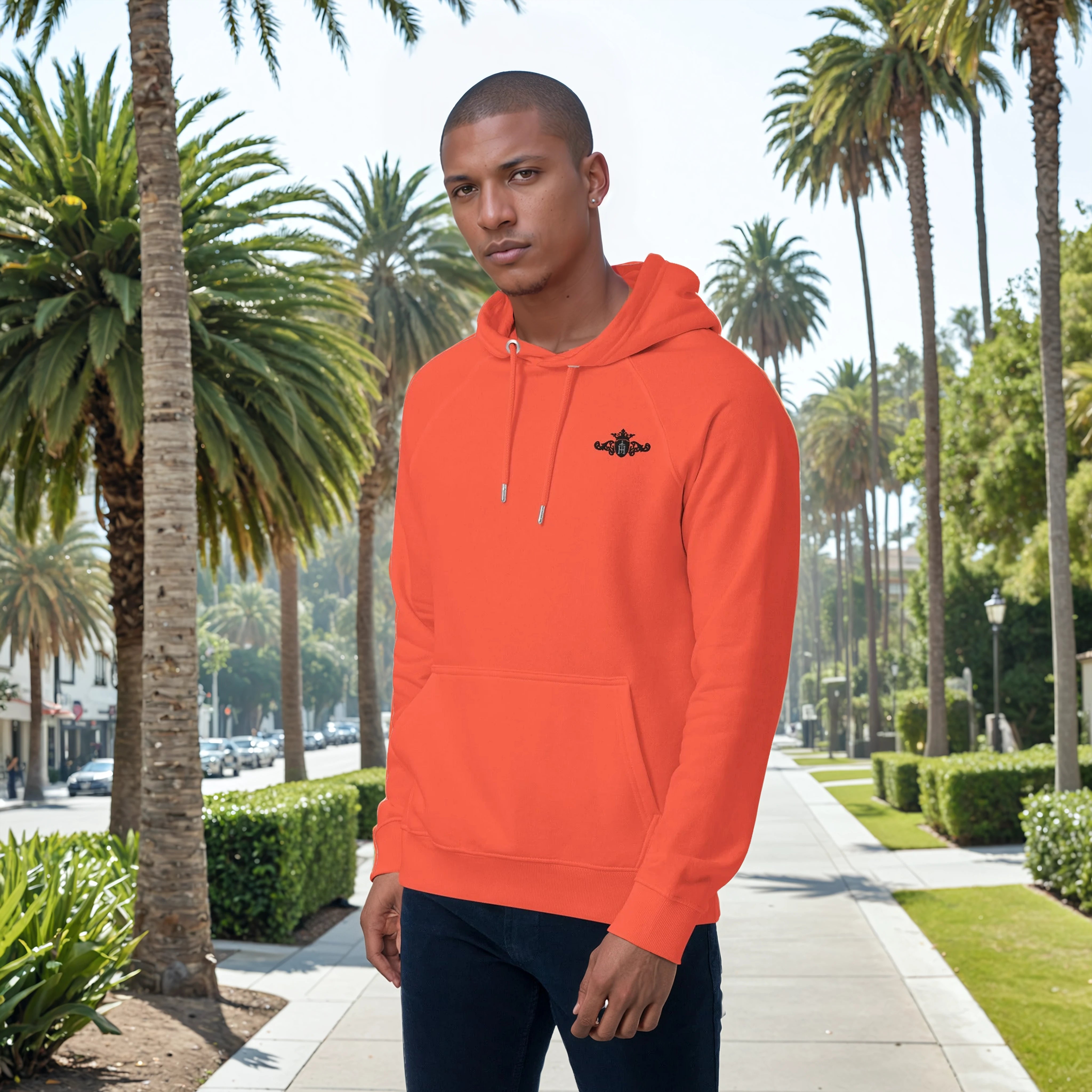 Man wearing an orange hoodie with a palm tree-lined street in the background