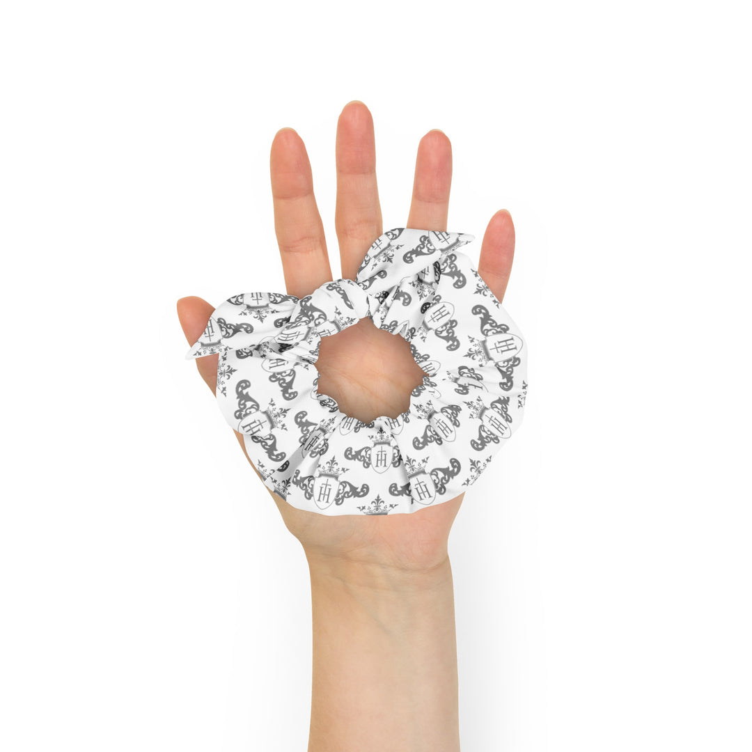 Hand holding a white scrunchie with black patterns on a white background