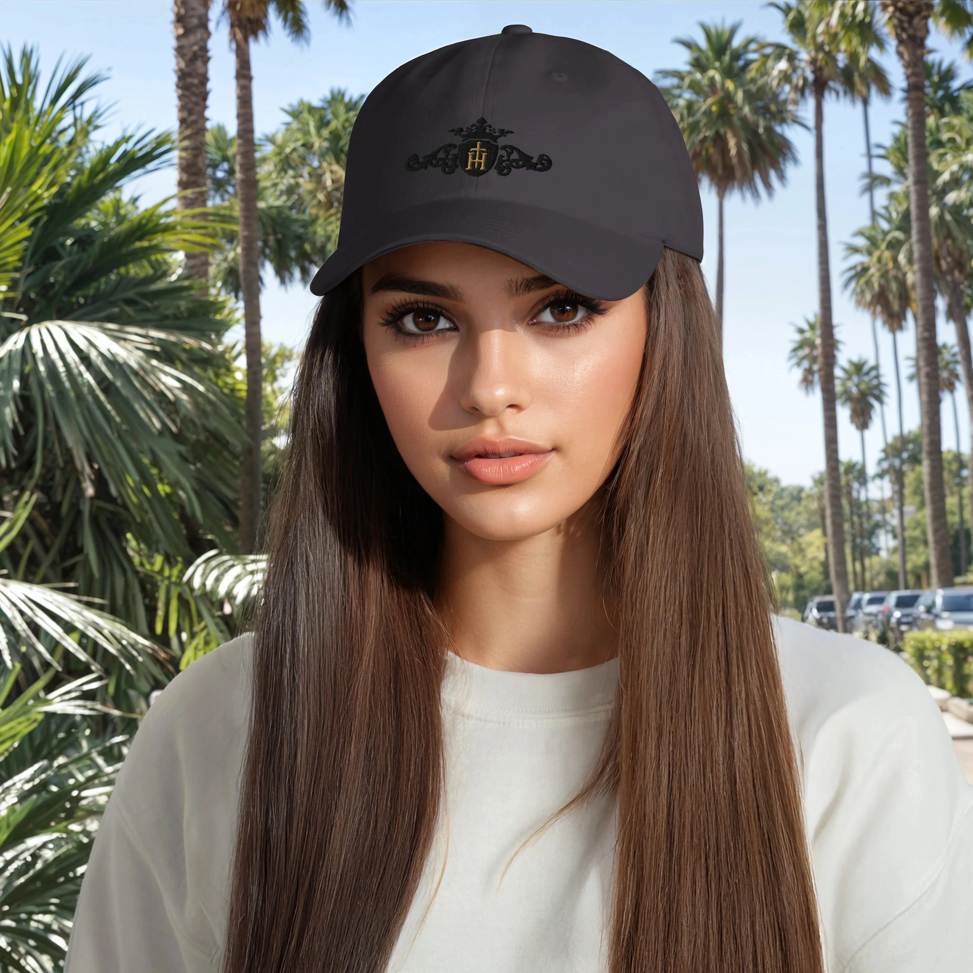 Woman wearing a dark gray cap with a logo in front of palm trees