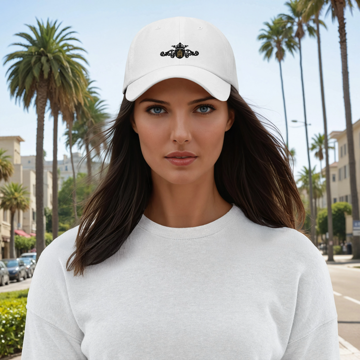 Woman wearing a white cap with a black and gold crest with a gold center in a palm tree-lined street.
