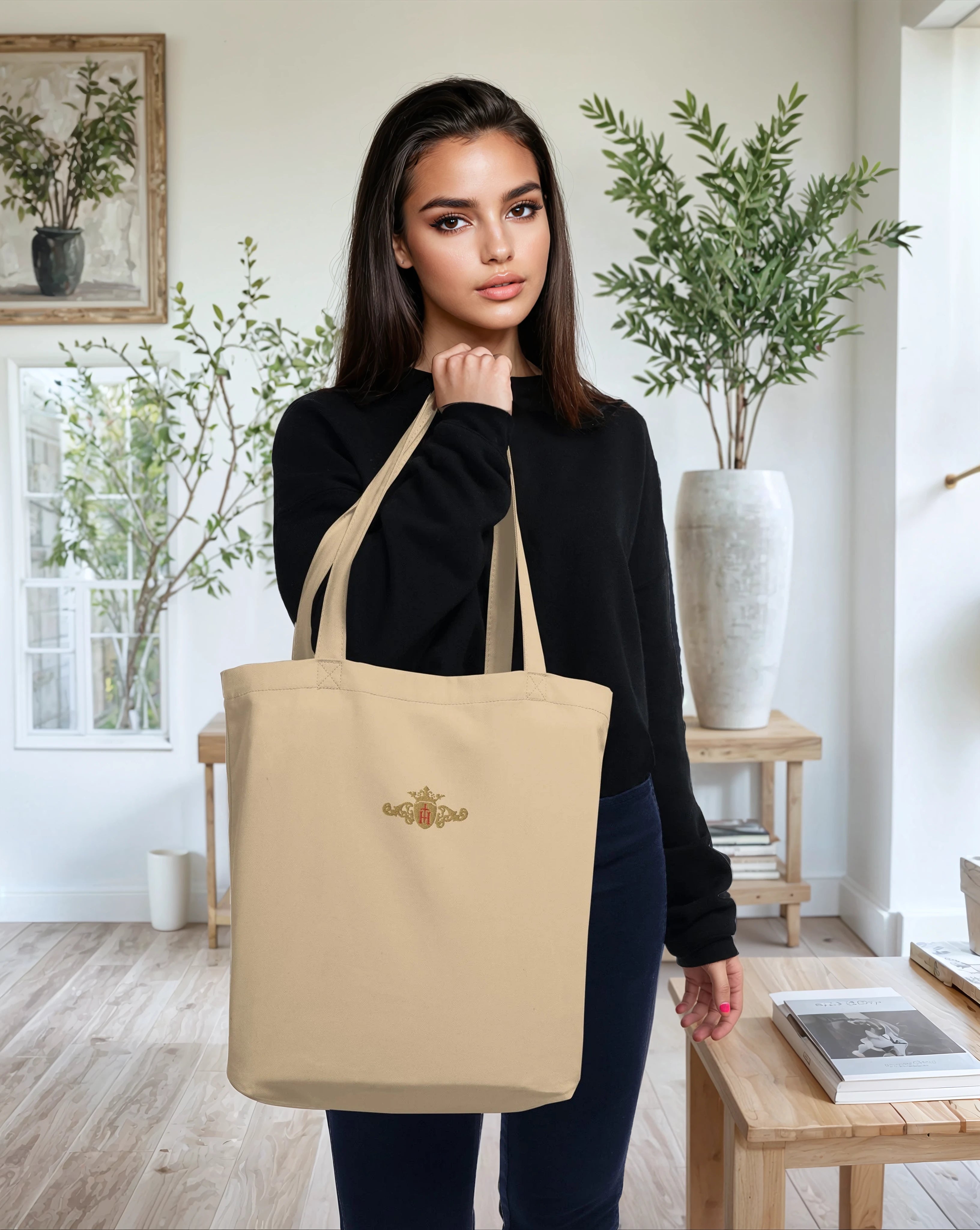 Woman holding a beige tote bag with a logo in a home setting