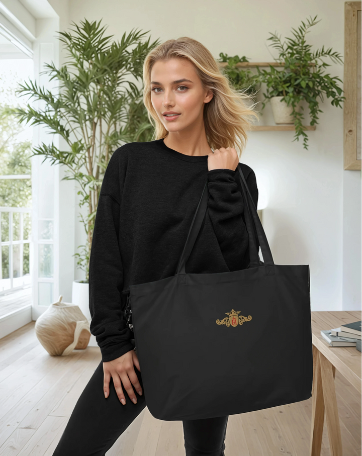 Woman holding a black tote bag with a logo in a bright room with plants
