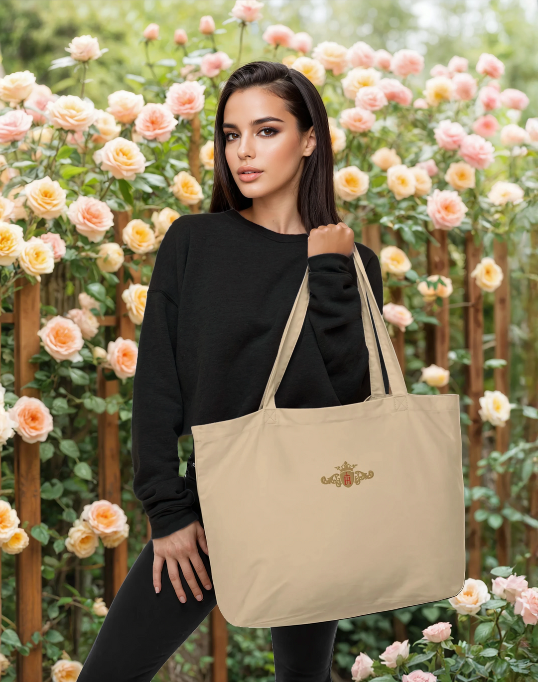 Woman holding a beige tote bag with a gold and red crest in front of a floral background
