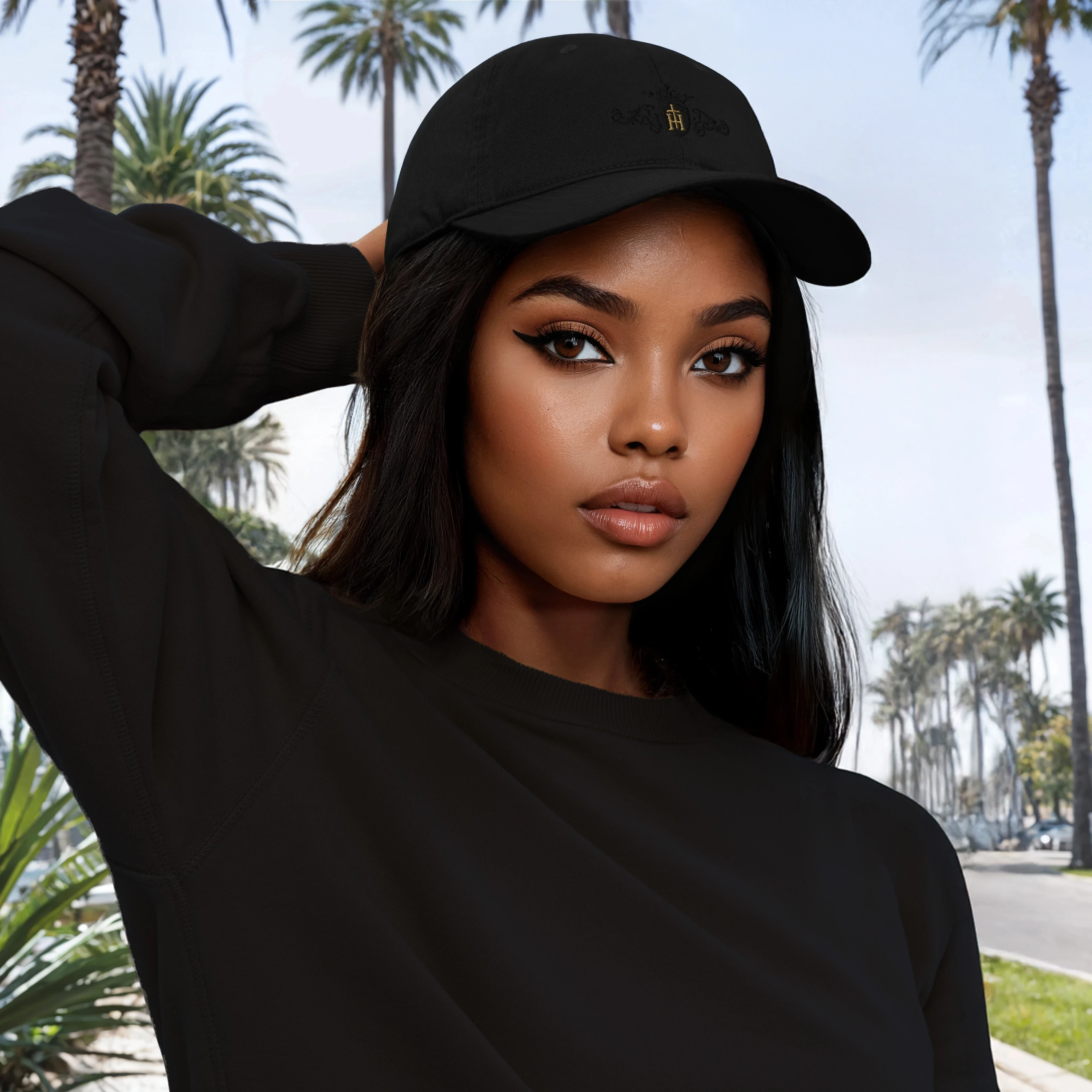 Woman wearing a black cap and sweatshirt with palm trees in the background
