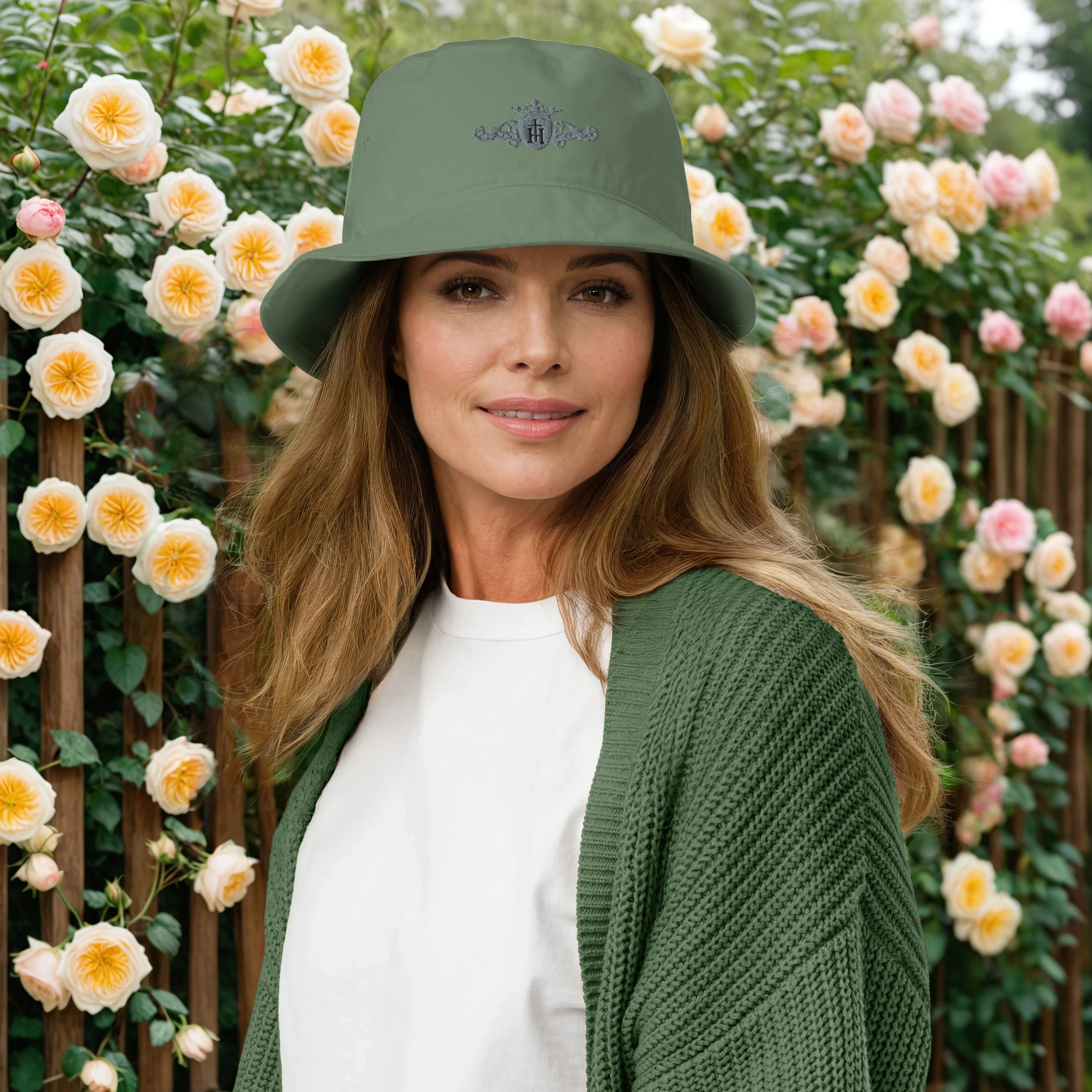 Woman wearing a green bucket hat and cardigan in front of flowering plants