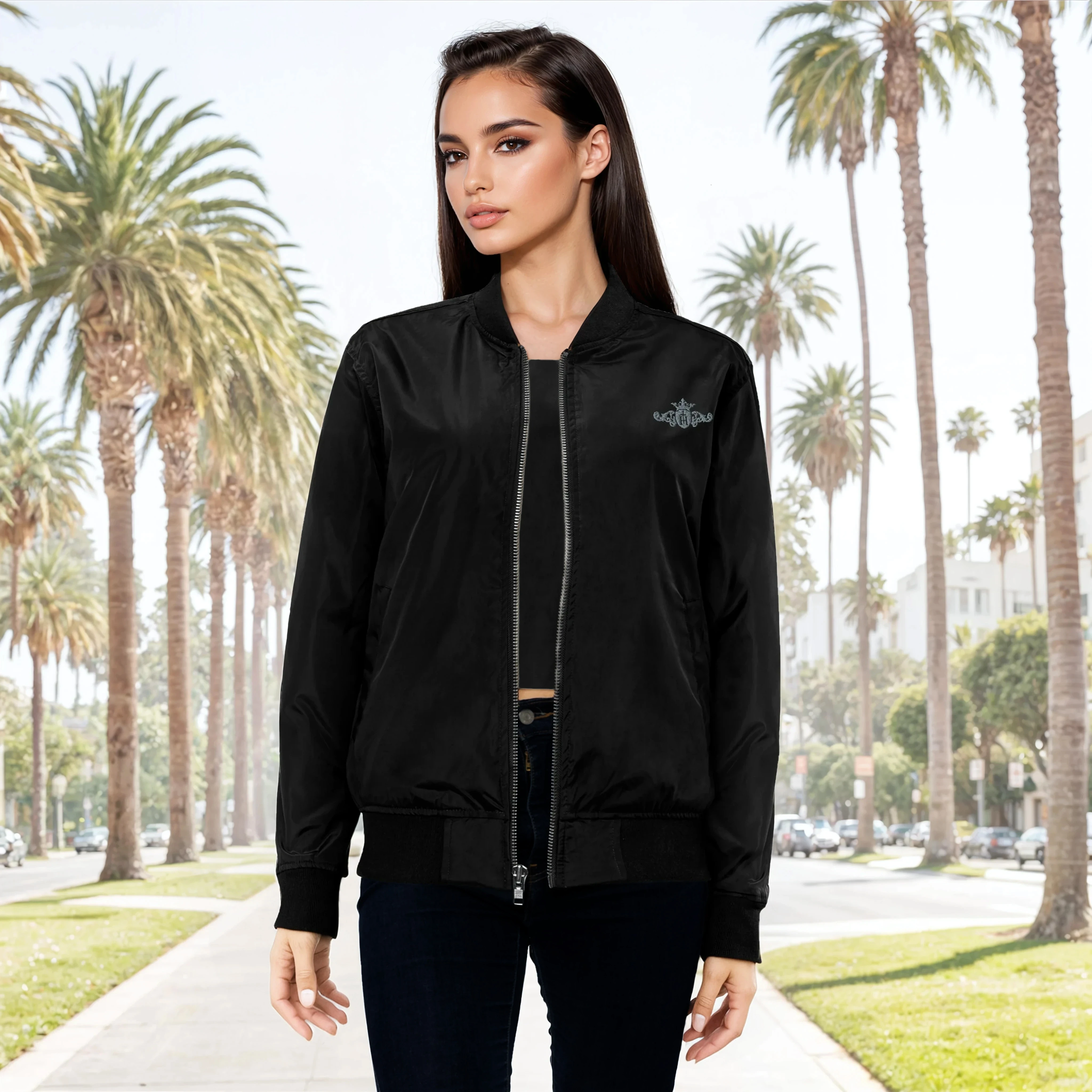 Woman wearing a black bomber jacket with a brand logo in front of palm trees.