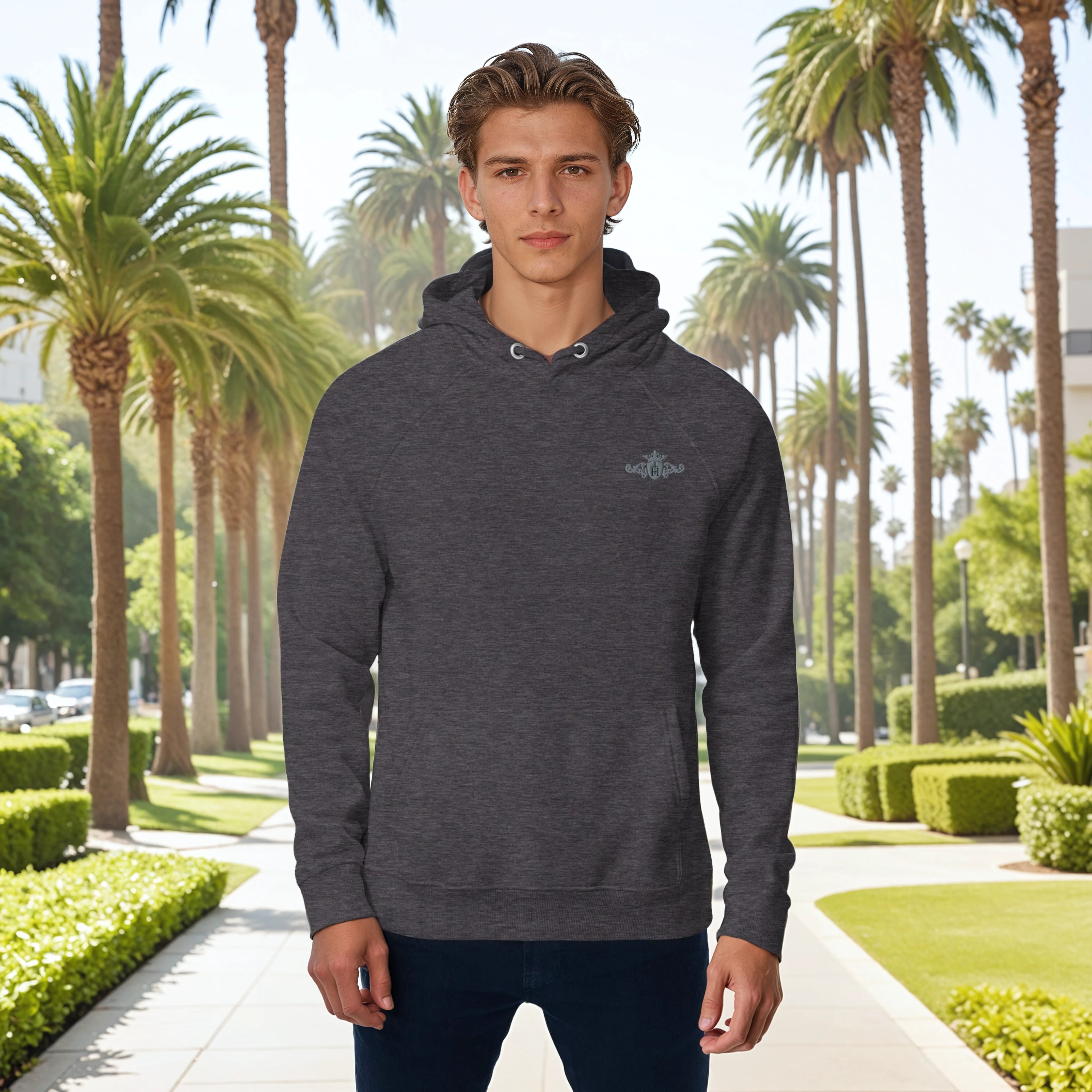 Man wearing a dark gray hoodie with a logo in front of palm trees