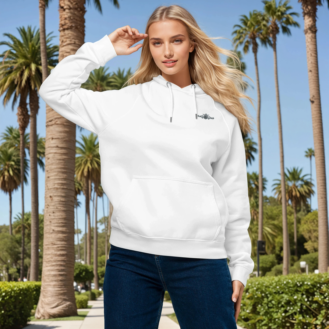 Woman wearing a white hoodie with a grey and black crest in a palm tree-lined park