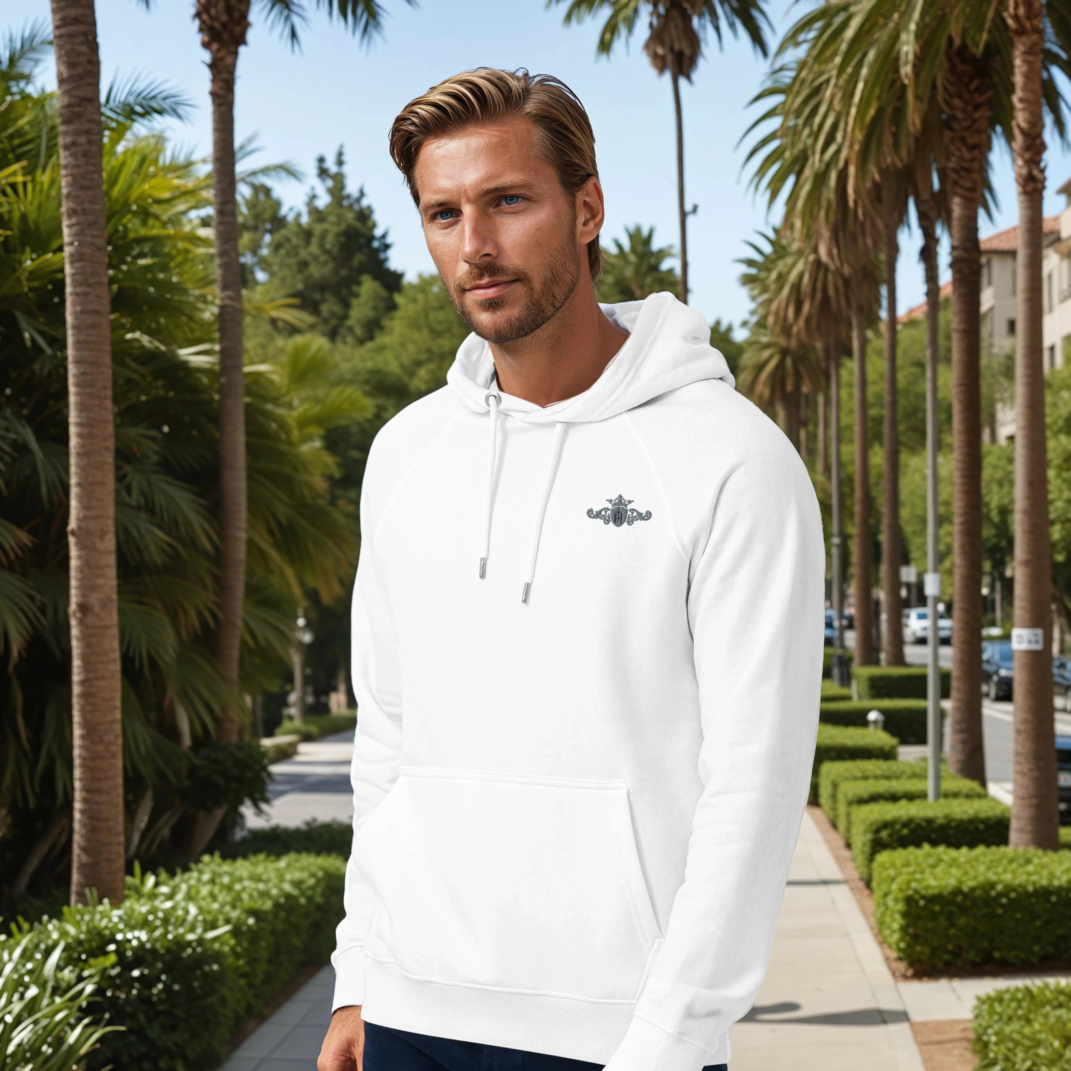 Man wearing a white hoodie with a logo in a palm tree-lined street
