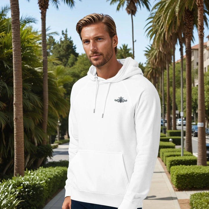Man wearing a white hoodie with a logo in a palm tree-lined street