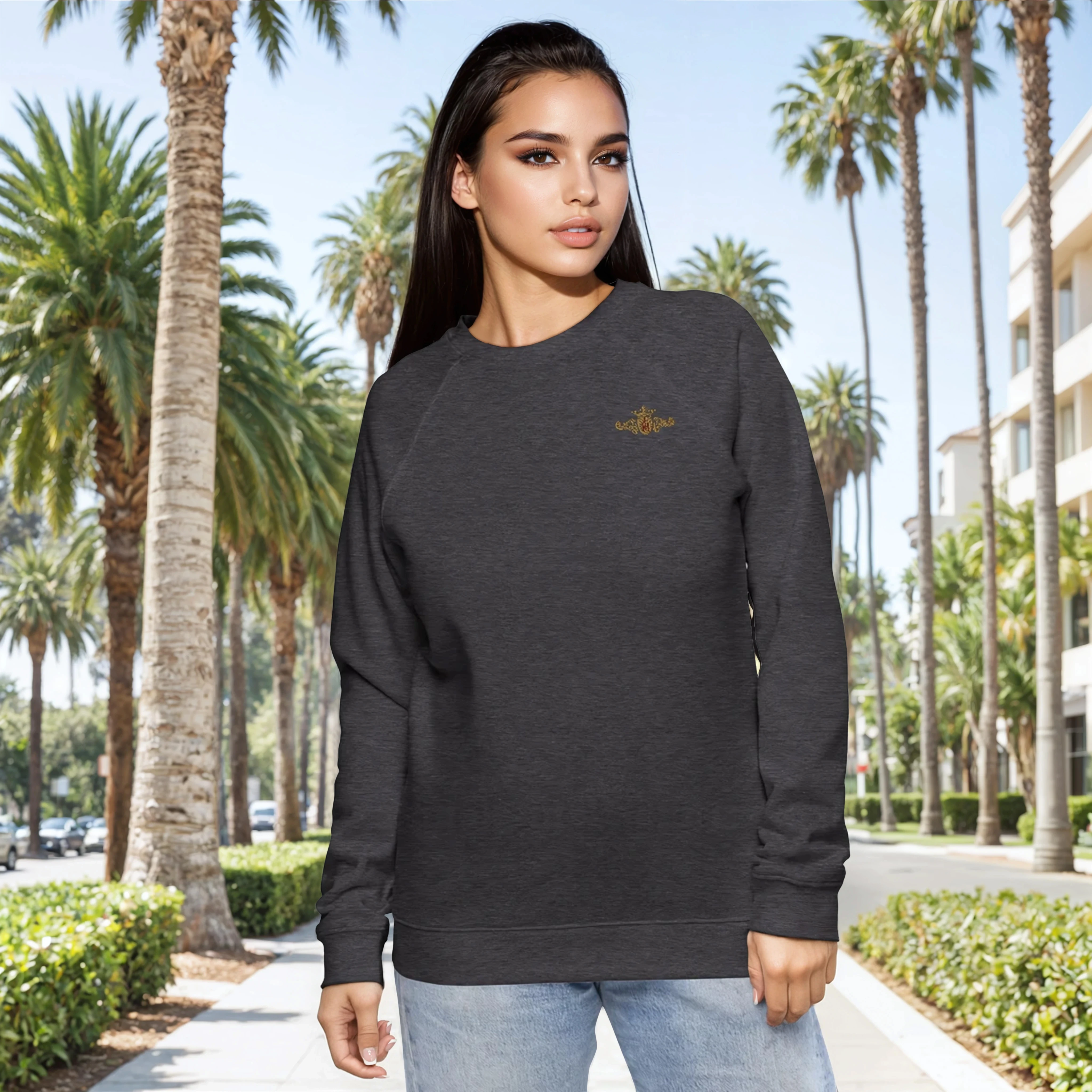 Woman wearing a dark gray sweatshirt with a gold and maroon crest in a palm tree-lined street.