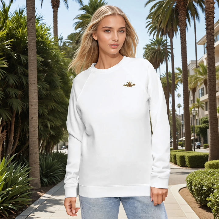 Woman wearing a white sweatshirt with a gold and maroon crest in a palm tree-lined street.