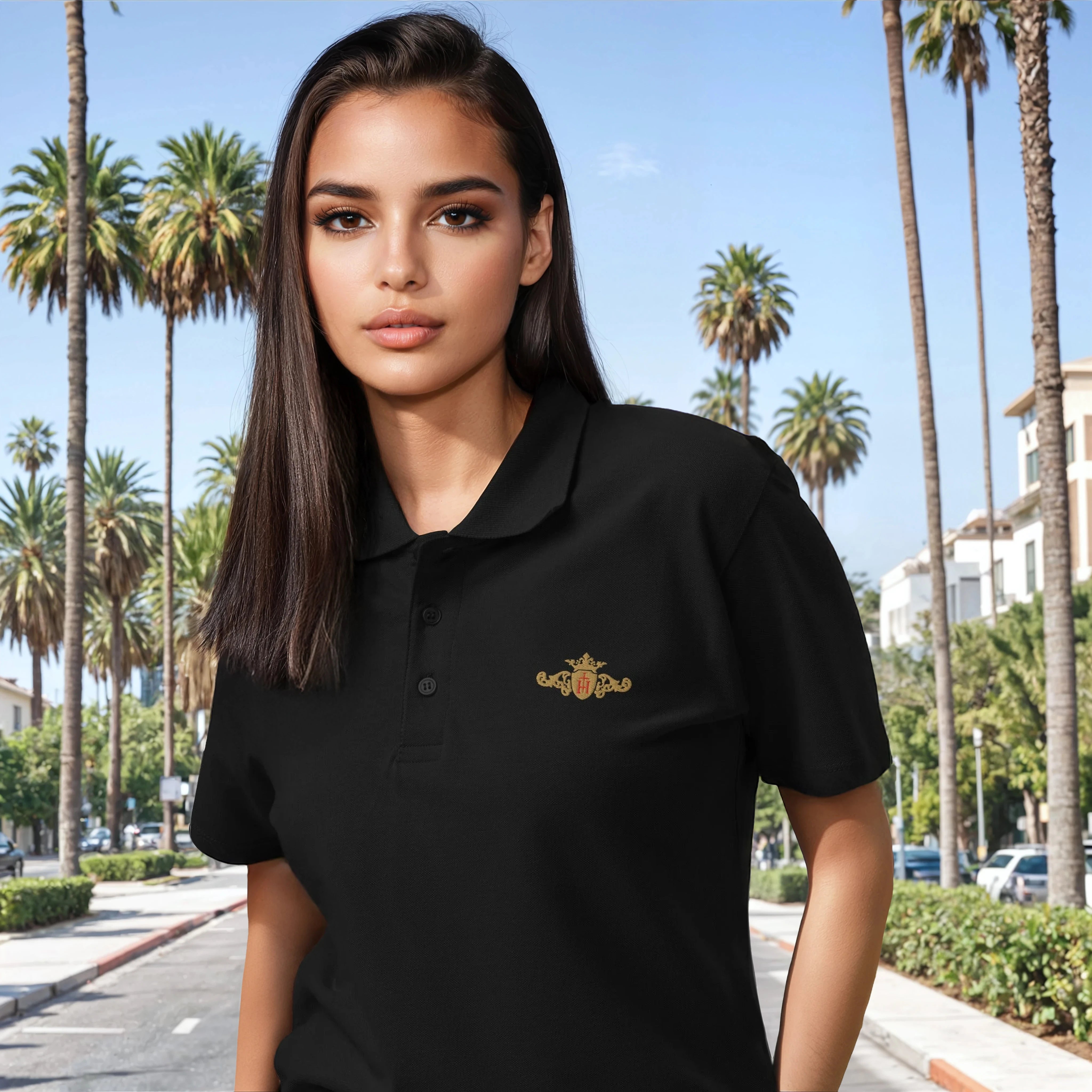 Woman wearing a black polo shirt with a logo in a palm tree-lined street.