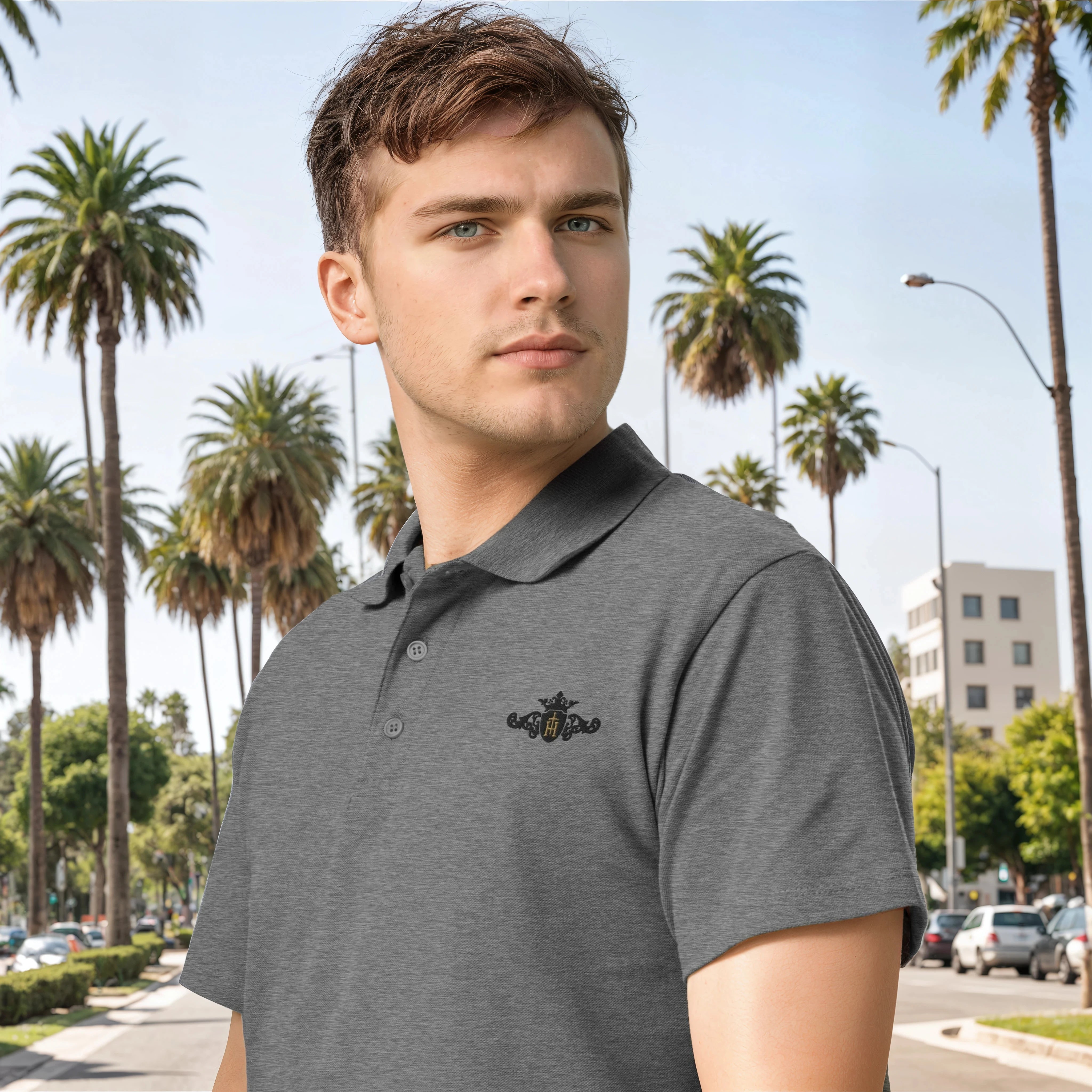 Man wearing a gray polo shirt with a logo in an urban setting with palm trees