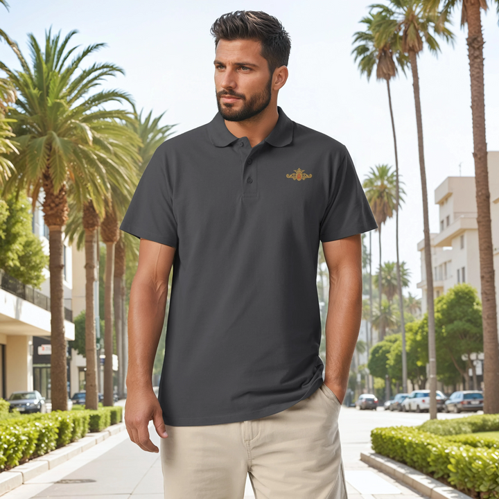 Man wearing a dark gray polo shirt with a gold and red crest, standing in a palm tree-lined street.