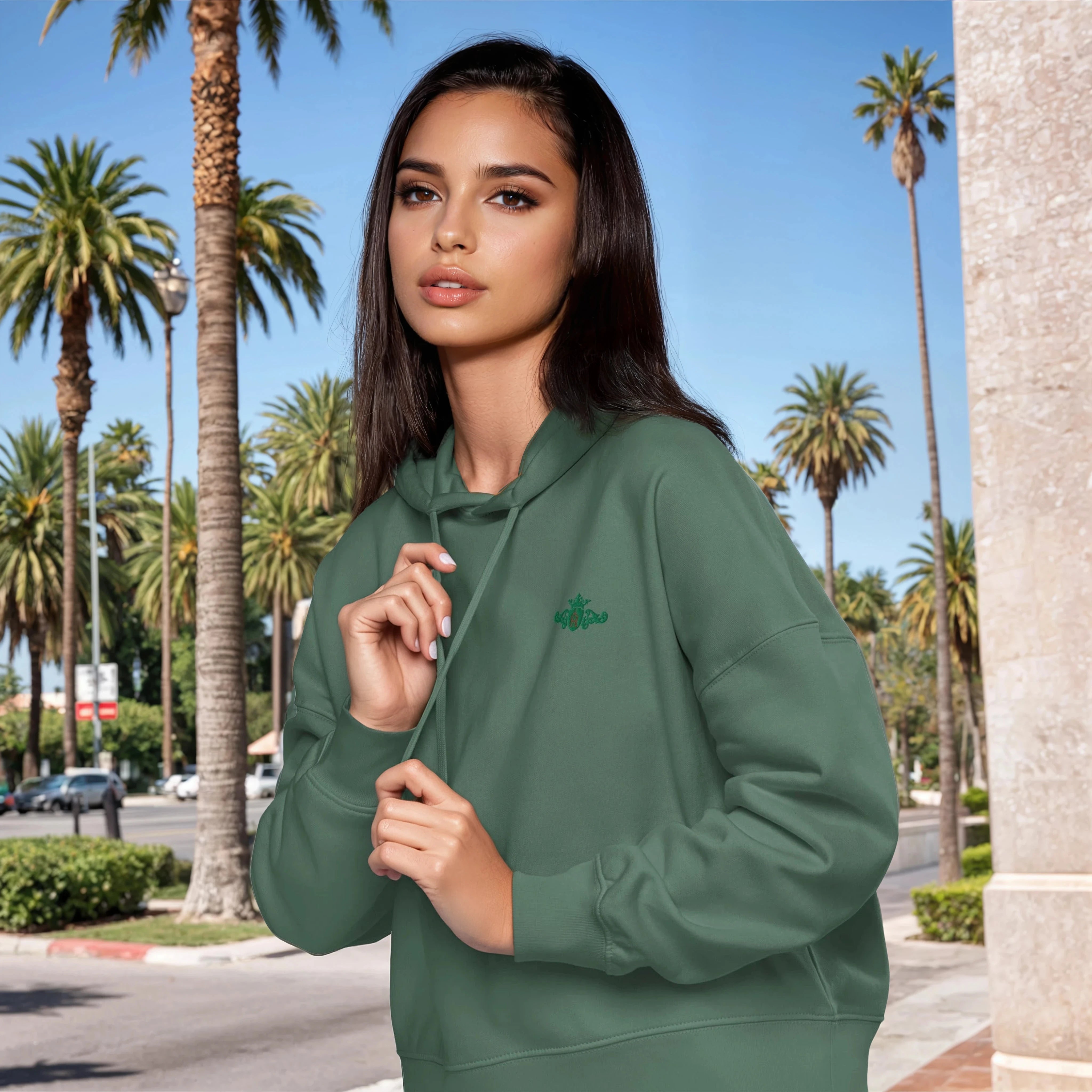 Woman wearing a green hoodie with a palm tree design in a sunny outdoor setting